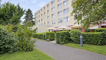 A pathway leading to a building with multiple windows and a flat roof.