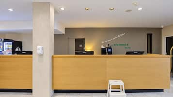 A reception desk with a wooden counter, a small white stool, and a wall with a motivational quote.