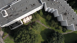 Una vista aerea di un edificio con tetto piatto, circondato da aree verdi e alberi.