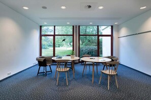 A conference room with a large window, a round table, and four chairs.