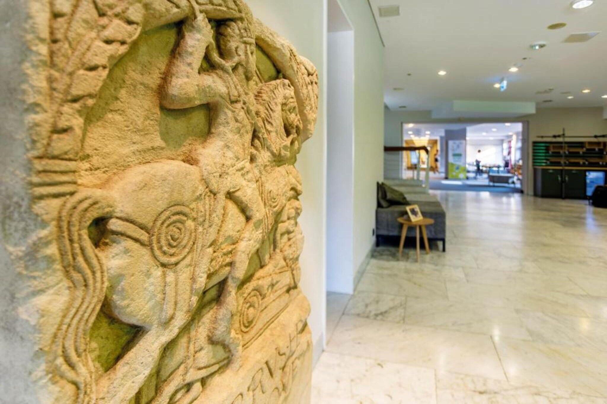 Un mur de pierre orné de sculptures complexes, un intérieur moderne avec un espace salon et un sol propre et poli.