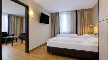 Une chambre d’hôtel avec un lit, un bureau, une chaise, une télévision et des rideaux.