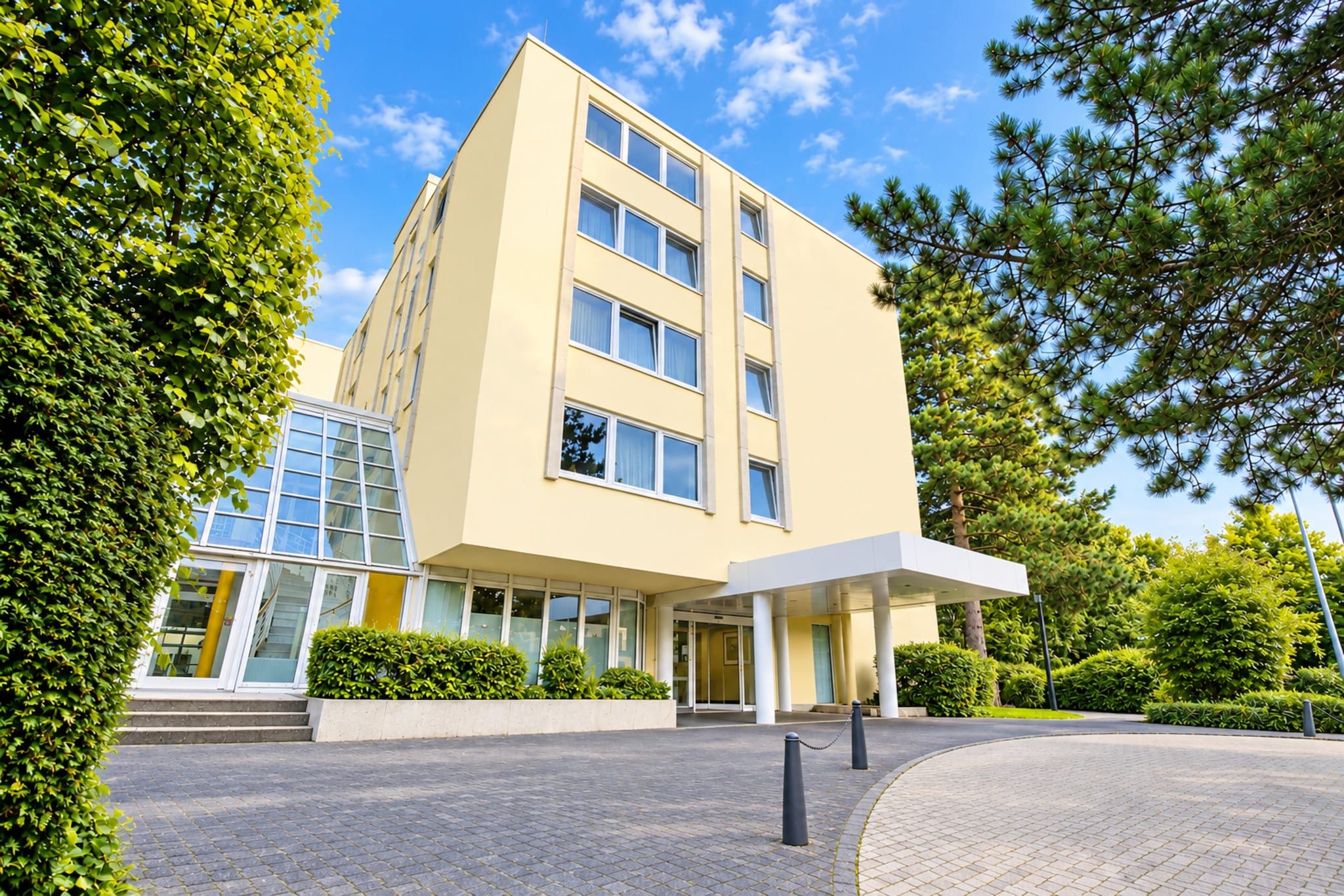 Un hôtel moderne à la façade sobre, doté de grandes fenêtres et d’une entrée abritée.