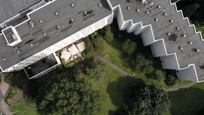 Una vista aerea di un edificio con tetto piatto, circondato da aree verdi e alberi.