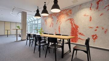A modern conference room with a long table, black chairs, and pendant lighting.