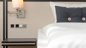 Ein ordentlich bezogenes Bett mit Kissen und einer Nachttischlampe.