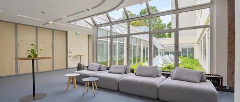 A modern lounge area with a sectional sofa, a small table, and a potted plant.