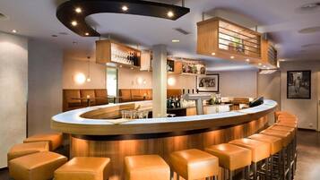 Eine Bar mit einer gebogenen Theke, mehreren Hockern und Regalen mit Flaschen darüber.