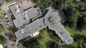 Ilmakuva rakennuksesta, jossa on useita pysäköintipaikkoja, uima-allas ja ympäröivää viheraluetta.