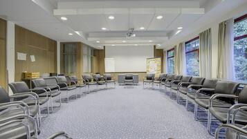 Une salle de conférence équipée d’une longue table, de chaises, d’un tableau blanc et d’un écran de projection.