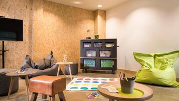 Un salon moderne comprenant un canapé, un fauteuil poire, une table basse, une bibliothèque et un téléviseur à écran plat fixé au mur.