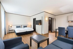Una habitación de hotel moderna con una cama doble, una mesita pequeña, dos sillas, un escritorio y un televisor montado en la pared.