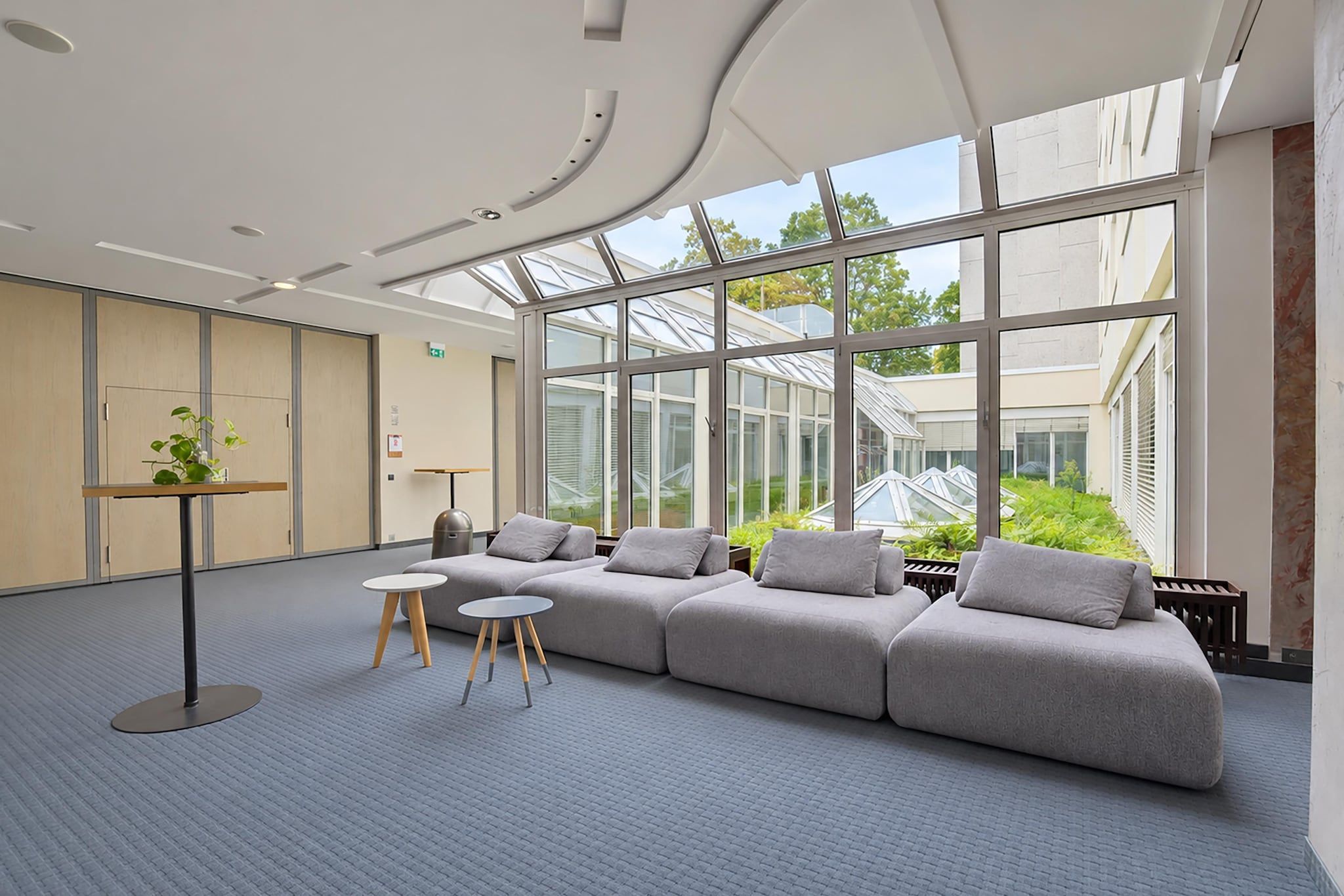 Et moderne opholdsområde med en hjørnesofa, et lille bord og en potteplante.