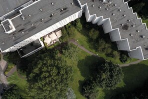 Vista aérea de un edificio con techo plano, rodeado de zonas verdes y árboles.