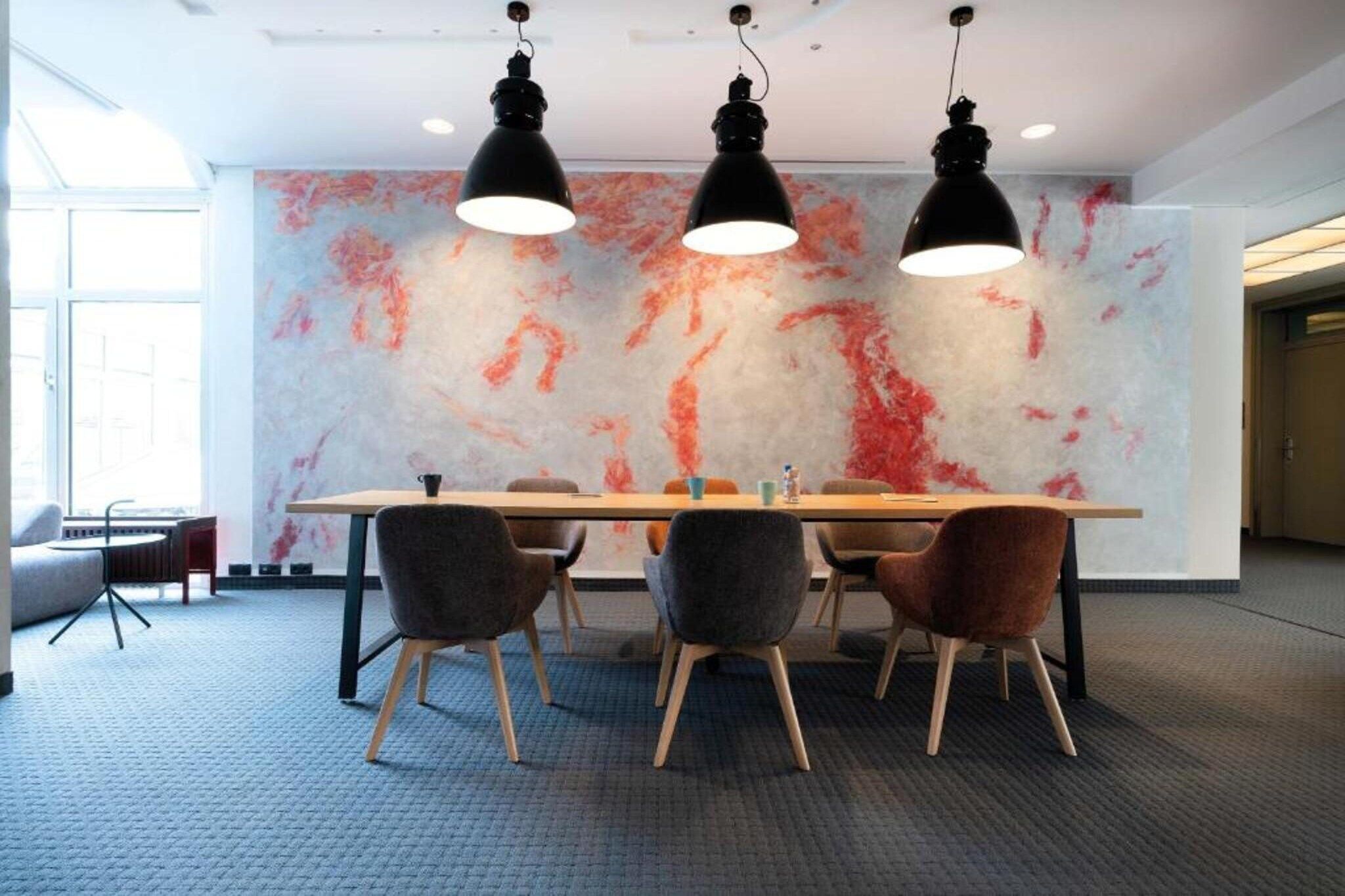 A conference room with a table, chairs, and pendant lights.