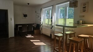 A modern kitchen with a dining area, wooden flooring, and a view through the windows. - Apartment 1 – Schrappmühle with Terrace, Garden, Wi-Fi, and Rural Seclusion (Aerzen)