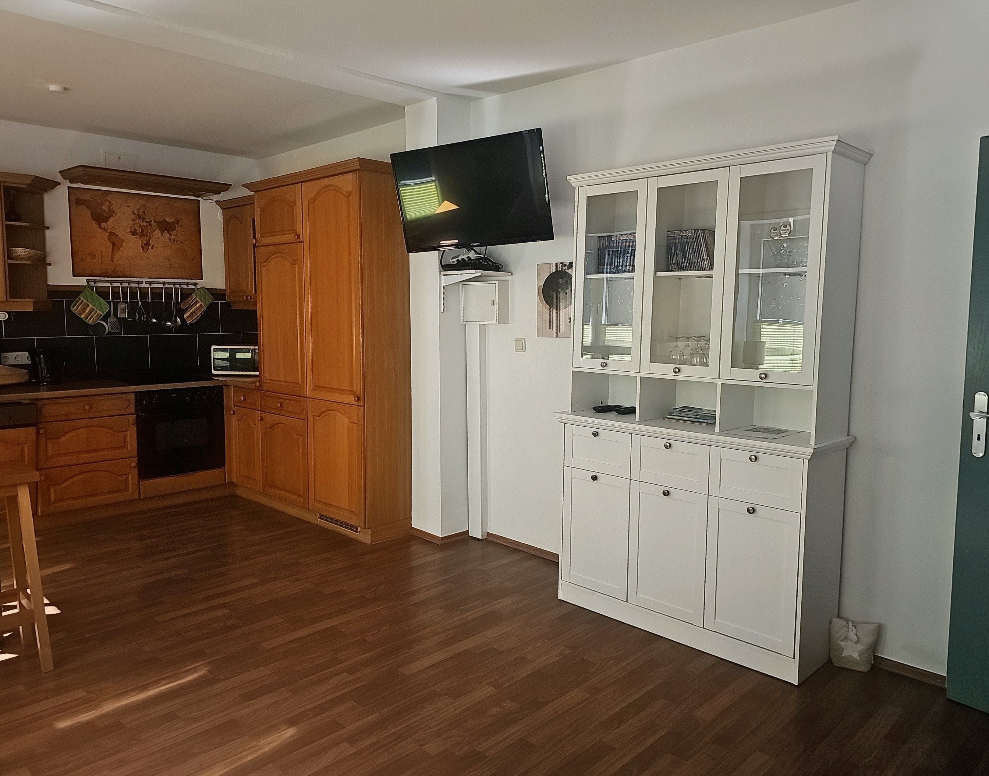 Eine Küche mit Holzschränken, einer Mikrowelle und einem an der Wand befestigten Fernseher.