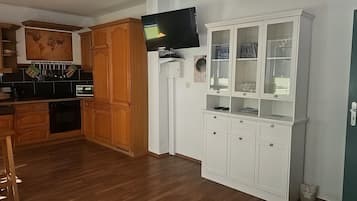 Une cuisine avec des meubles en bois, un four à micro-ondes et un téléviseur fixé au mur.