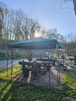 A park with a covered picnic area, benches, and a paved walkway.