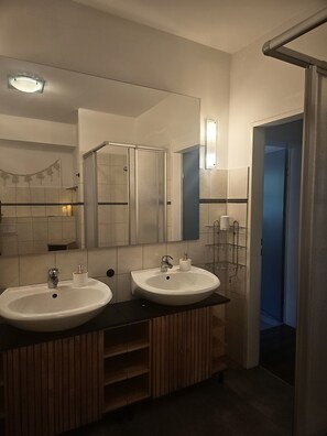 Ein Badezimmer mit zwei Waschbecken, einem Spiegel und einer Duschkabine.