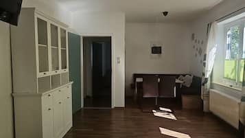 Une pièce avec un plancher en bois, une armoire aux portes vitrées, un lit avec des oreillers, un luminaire suspendu et une fenêtre avec des stores.