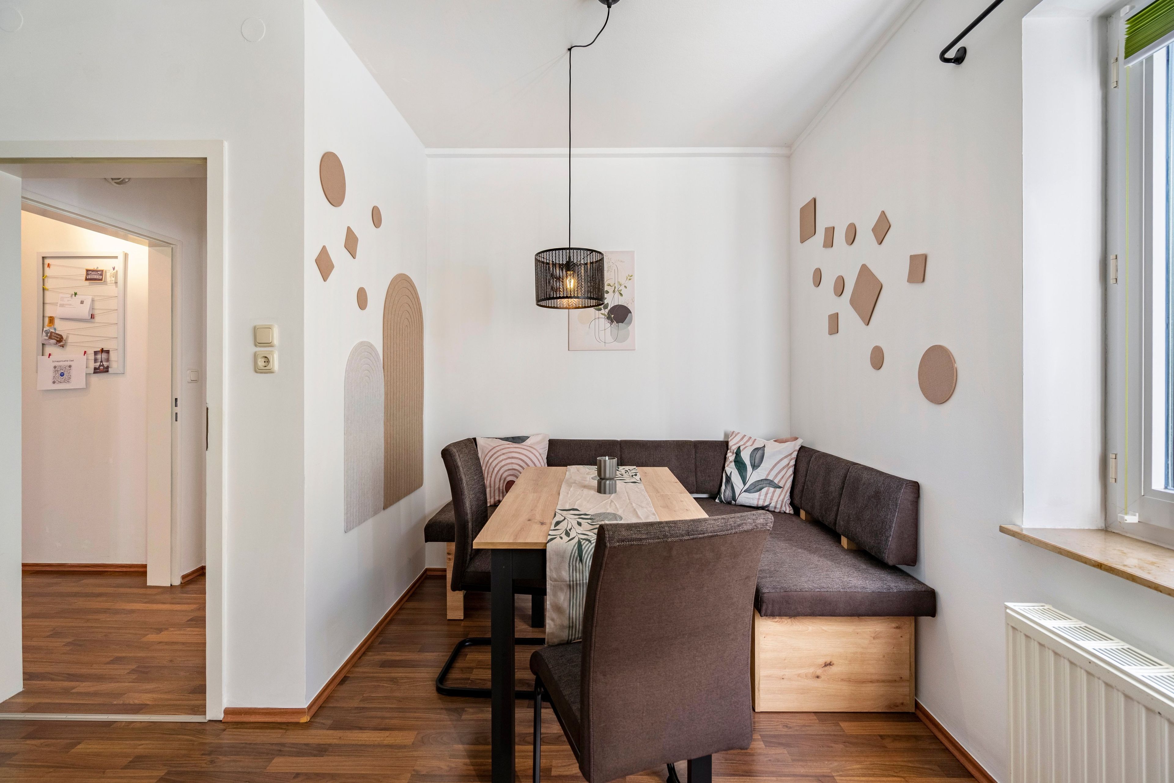 Ein moderner Essbereich mit einem Holztisch, einer braunen Couch und einer hängenden Leuchte.