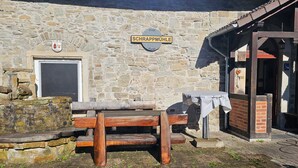 A stone building with a wooden bench and a table, a door, and a sign that reads 'SCHRAPPMÜHLE'. - Apartment 1 – Schrappmühle with Terrace, Garden, Wi-Fi, and Rural Seclusion (Aerzen)