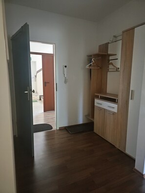Une pièce avec une armoire en bois, un petit bureau et une porte qui donne sur une autre pièce.