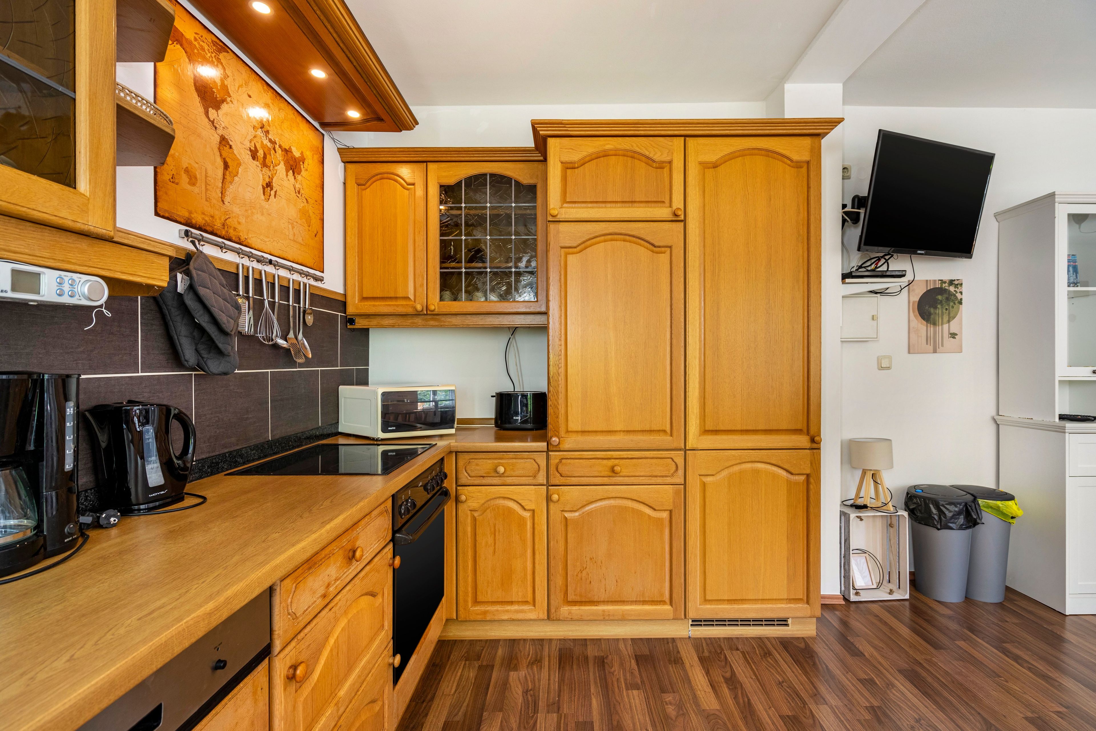 Eine moderne Küche mit Holzausstattung, einer Mikrowelle, einem Toaster und einer Kaffeemaschine.