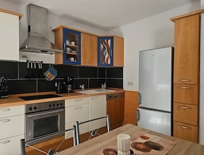 A modern kitchen with stainless steel appliances, wooden cabinets, and a tiled backsplash.