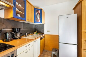 Una cocina compacta con estufa integrada, cafetera y refrigerador.