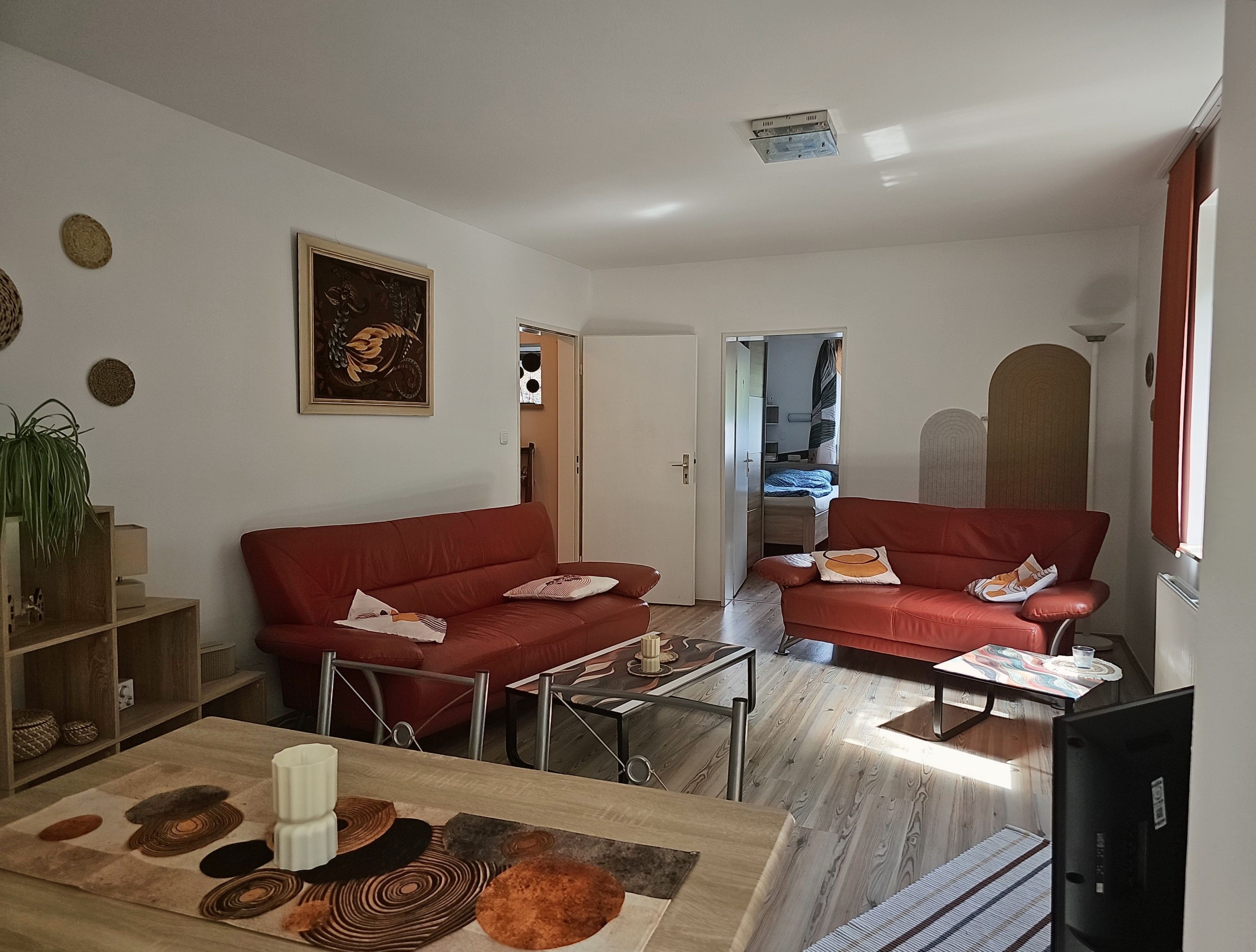 Een woonkamer met twee rode banken, een salontafel en een televisie.