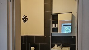 Et badeværelse med toilet, vask og spejl.