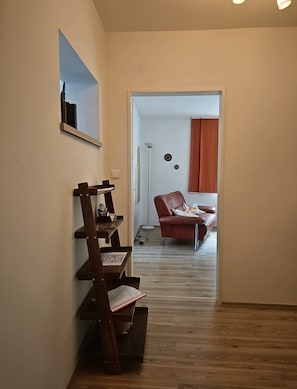 A hallway with a wooden chair, a red sofa, and a mirror on the wall.