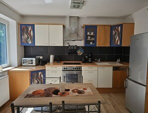 A modern kitchen with white and wooden cabinets, a built-in oven, a sink, and a dining table with a placemat.
