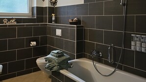 Un baño moderno con bañera, ducha y ventana que proporciona luz natural.