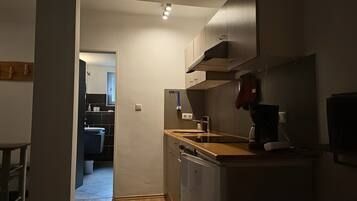 A compact kitchen with a dishwasher, a coffee machine, and a microwave.