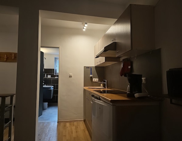 A compact kitchen with a dishwasher, a coffee machine, and a microwave.