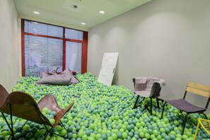 A room with a ball pit, two chairs, a window with blinds, and a whiteboard. - Seminaris Sunday Hotel Bad Honnef - Standard Single Room (Bad Honnef am Rhein)