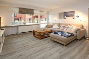 A modern living room with a sofa, coffee table, and a painting on the wall. - Holiday apartment with 2 bedrooms (Wyk auf Föhr)
