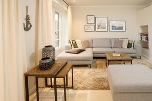 Ein Wohnzimmer mit einer Couch, zwei Couchtischen, einem Teppich und einem Kamin.
