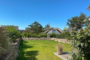 Ein gepflegter Garten mit einer Steinmauer, einem Rasen und einem Haus im Hintergrund.