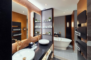 Un baño moderno con una bañera independiente, un espejo grande y un lavabo con tocador.