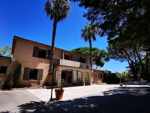 A two-story building with a flat roof, large windows, and a paved entrance area. - Le Mas Provencal (Gassin)