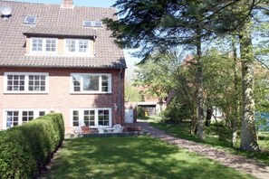 A two-story brick house with a paved driveway and a small patio area. - Holiday home with 2 bedrooms (Wyk auf Föhr)