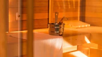 A sauna with a metal bucket containing a brush and a wooden bench.
