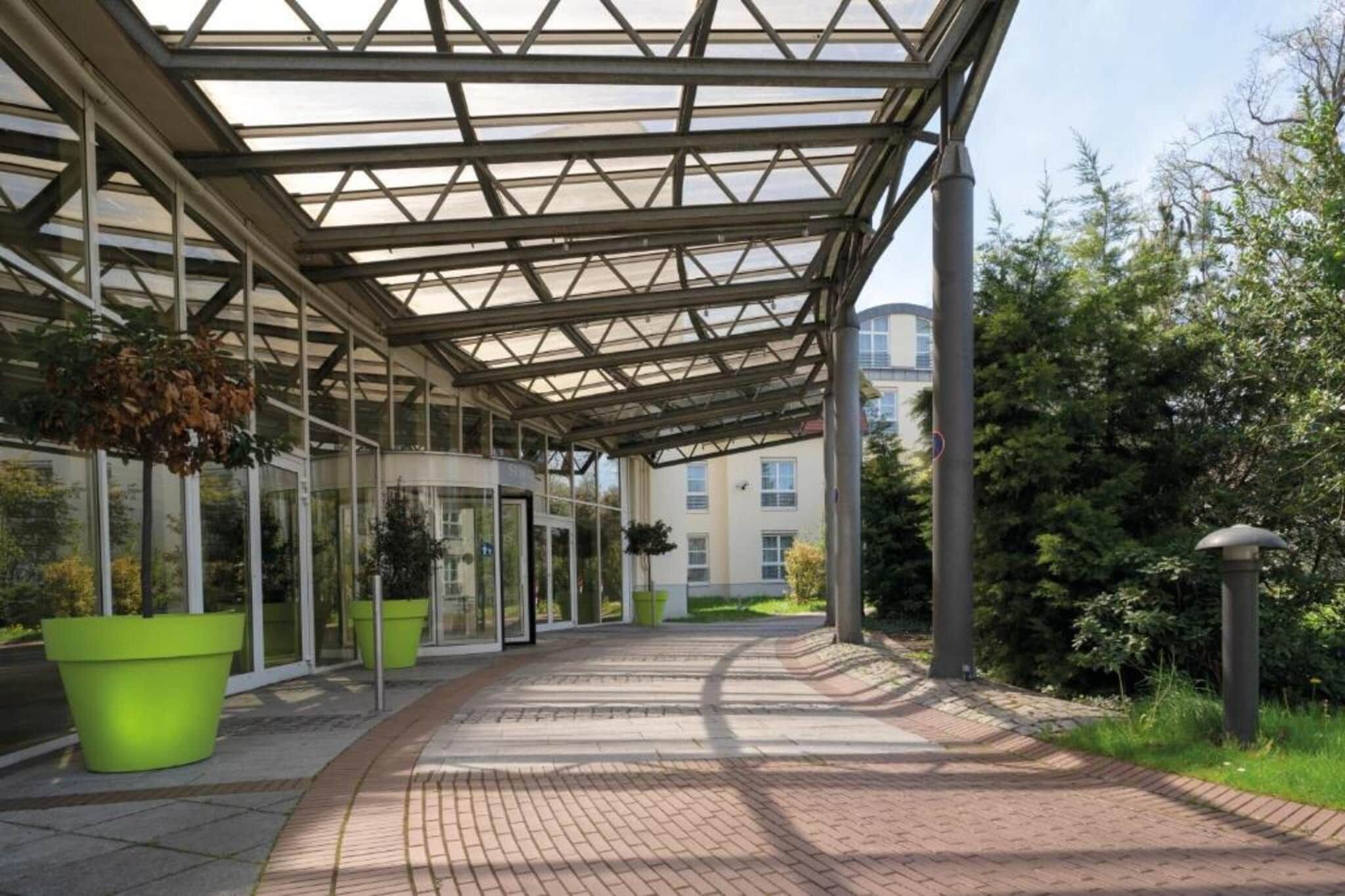 A covered walkway with glass panels and potted plants.