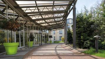 A covered walkway with glass panels and potted plants.