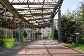 A covered walkway with glass panels and potted plants.