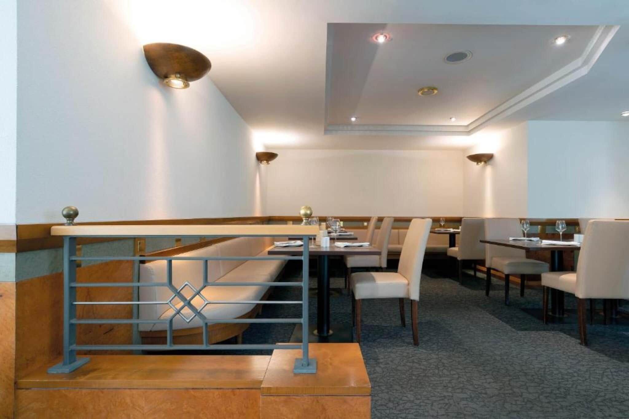 A restaurant with a high ceiling, recessed lighting, and a modern design.